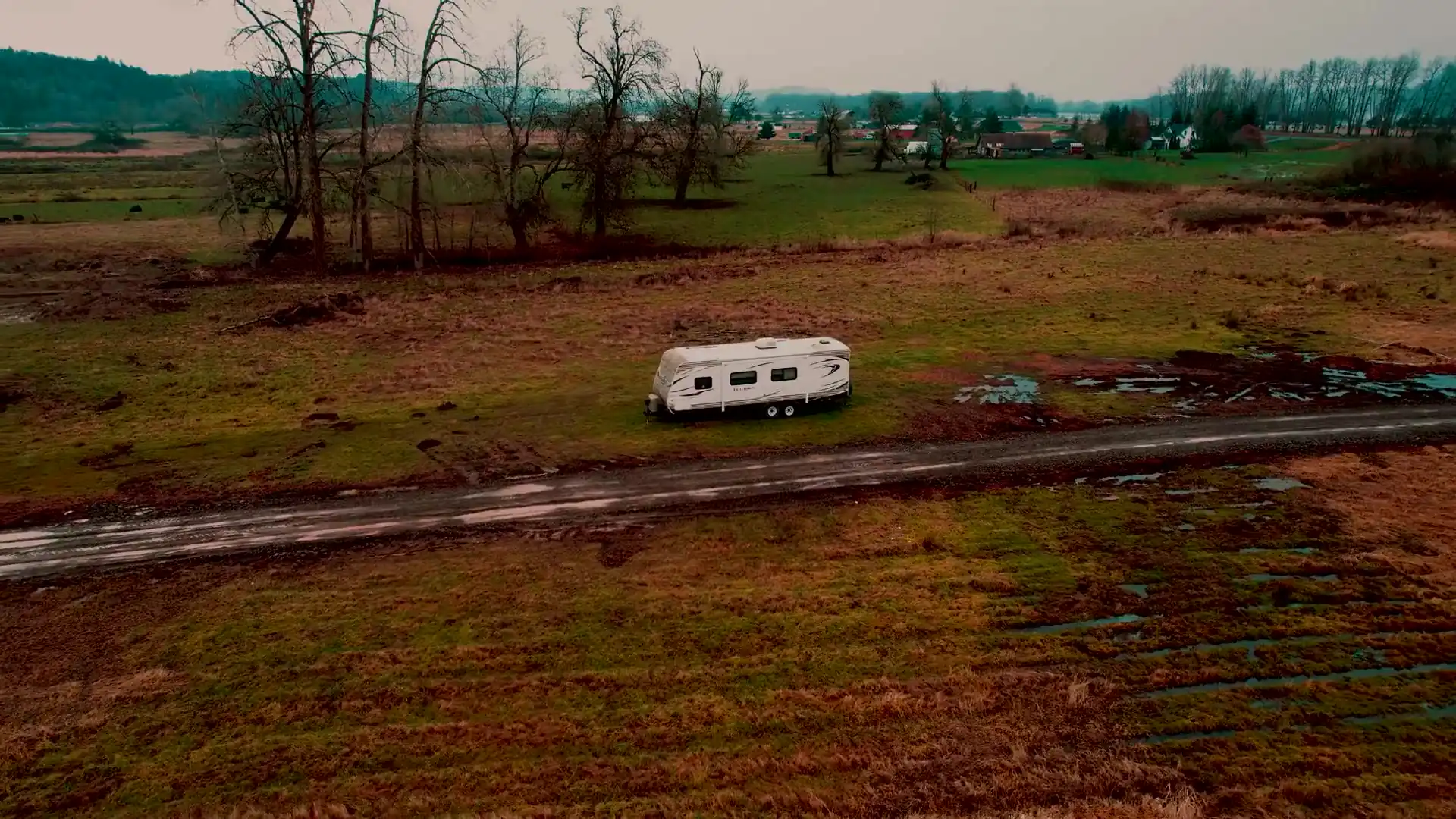 Aerial view of a travel trailer on a dirt road through open country