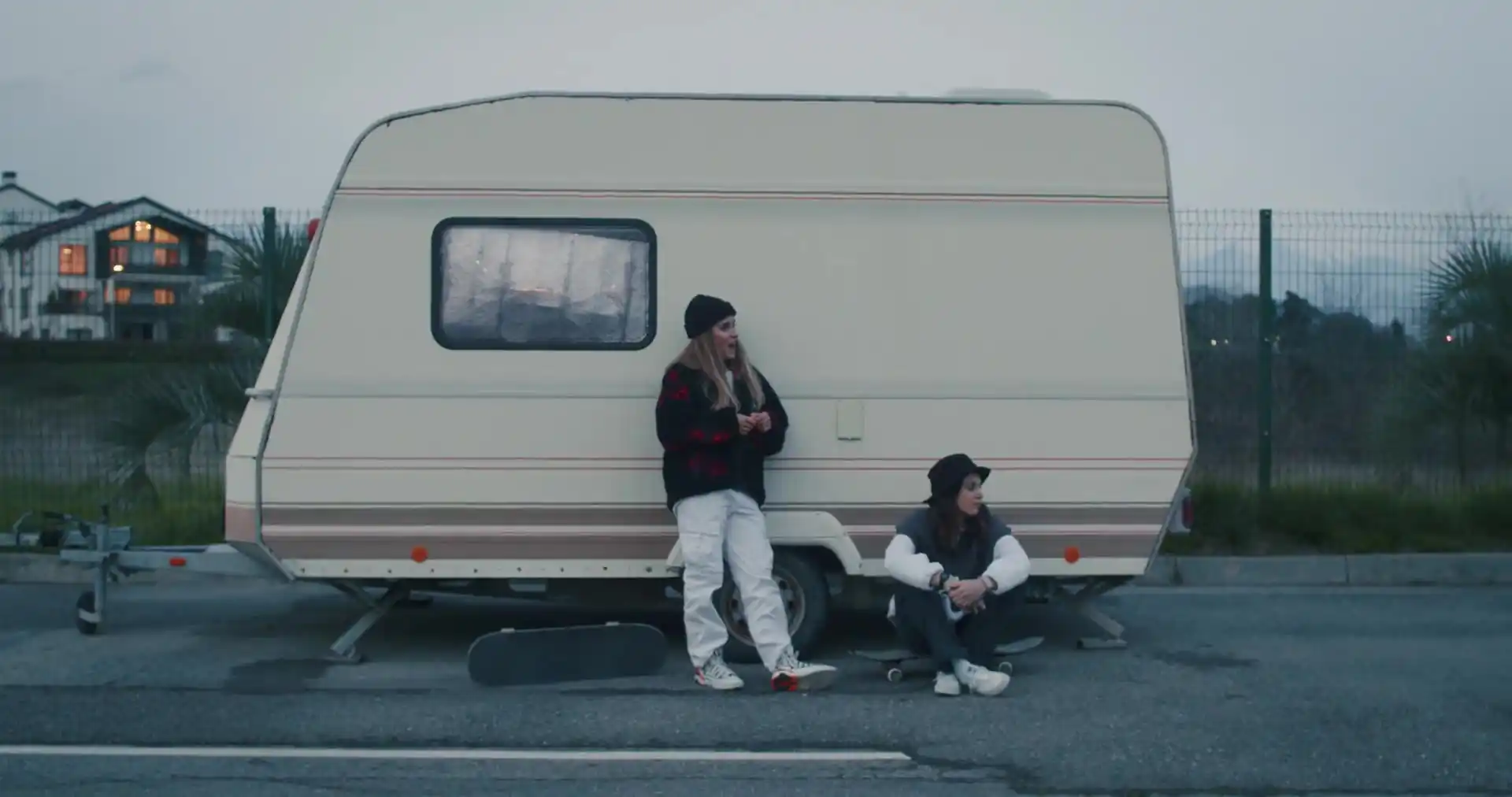 Two friends relaxing against a vintage camper