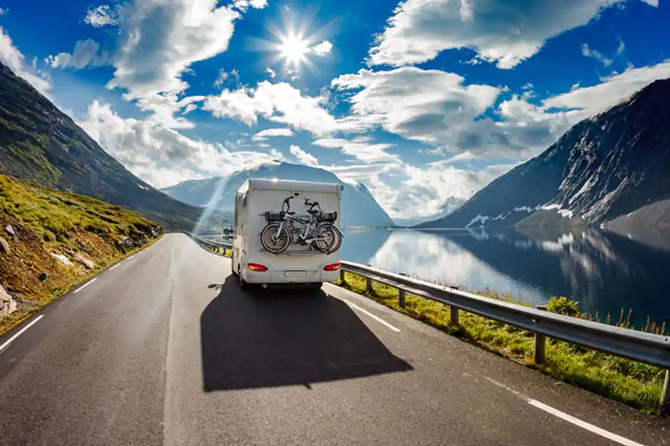 Motorhome with a bike rack driving along a lakeside mountain road